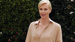 Charlize Theron che show in minigonna nera a Milano