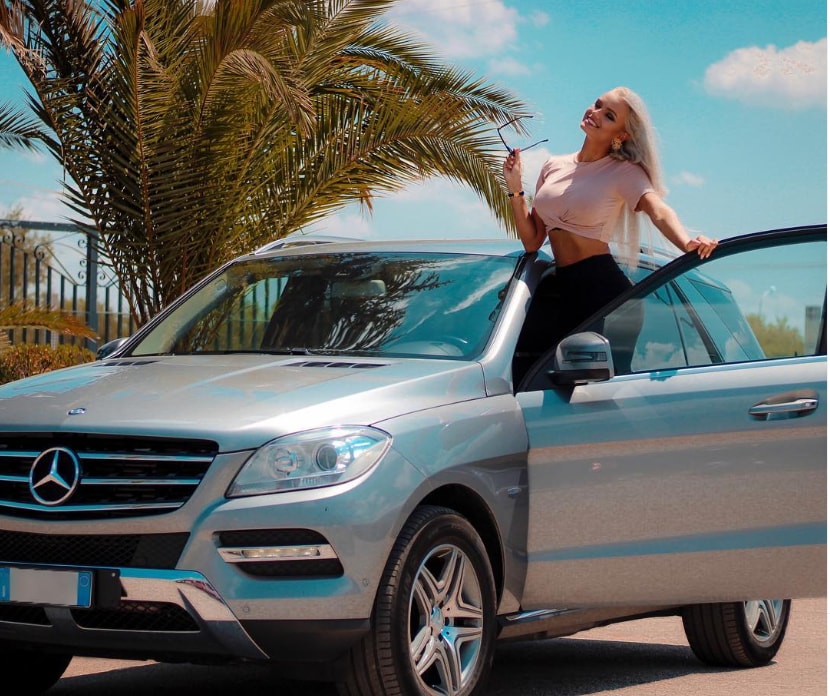 Mercedesz Henger a bordo dell'iconico SUV Mercedes, con un panorama estivo